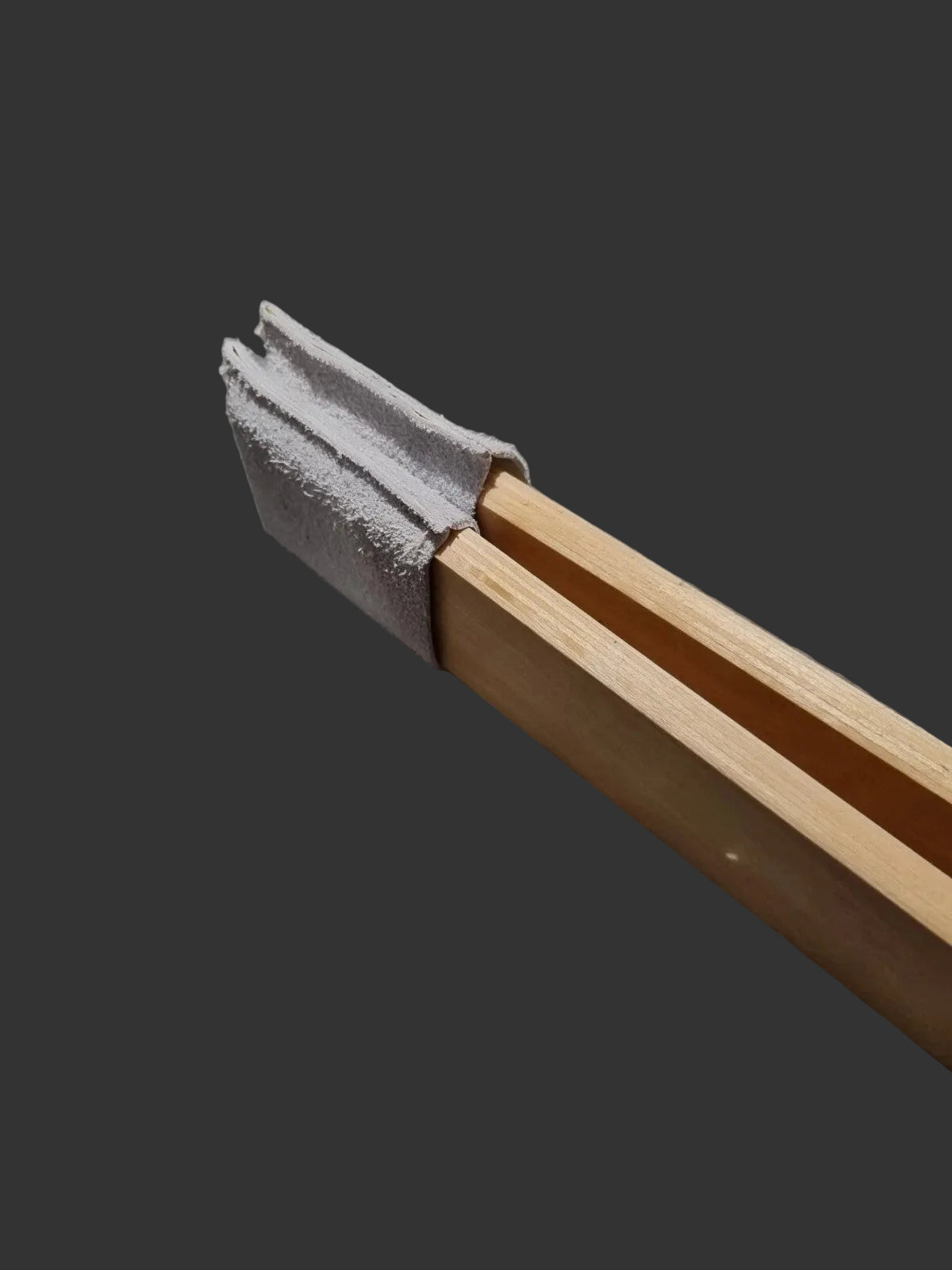A close-up of a pair of wooden slats with a grey leather socks to protect work wrapped around the jaws of the clam