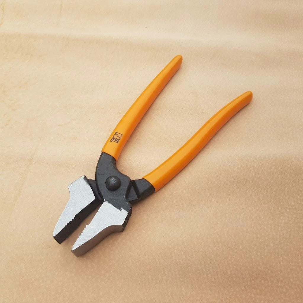 A pair of straight nose lasting pliers for pulling uppers with bright orange handles and silver metal jaws, resting on a textured beige surface.
