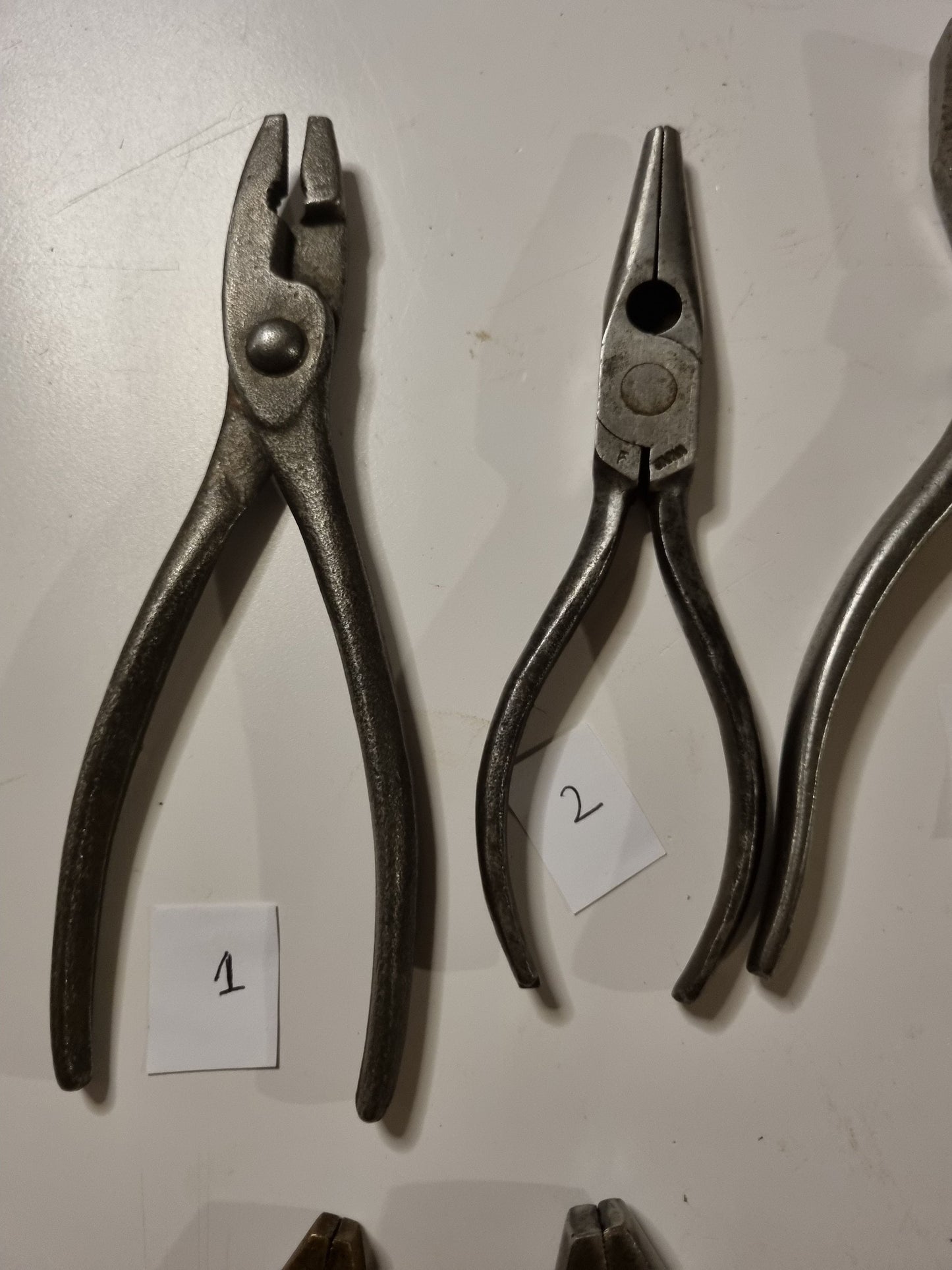 close view of vintage metal pliers titles 1 and 2 on white background