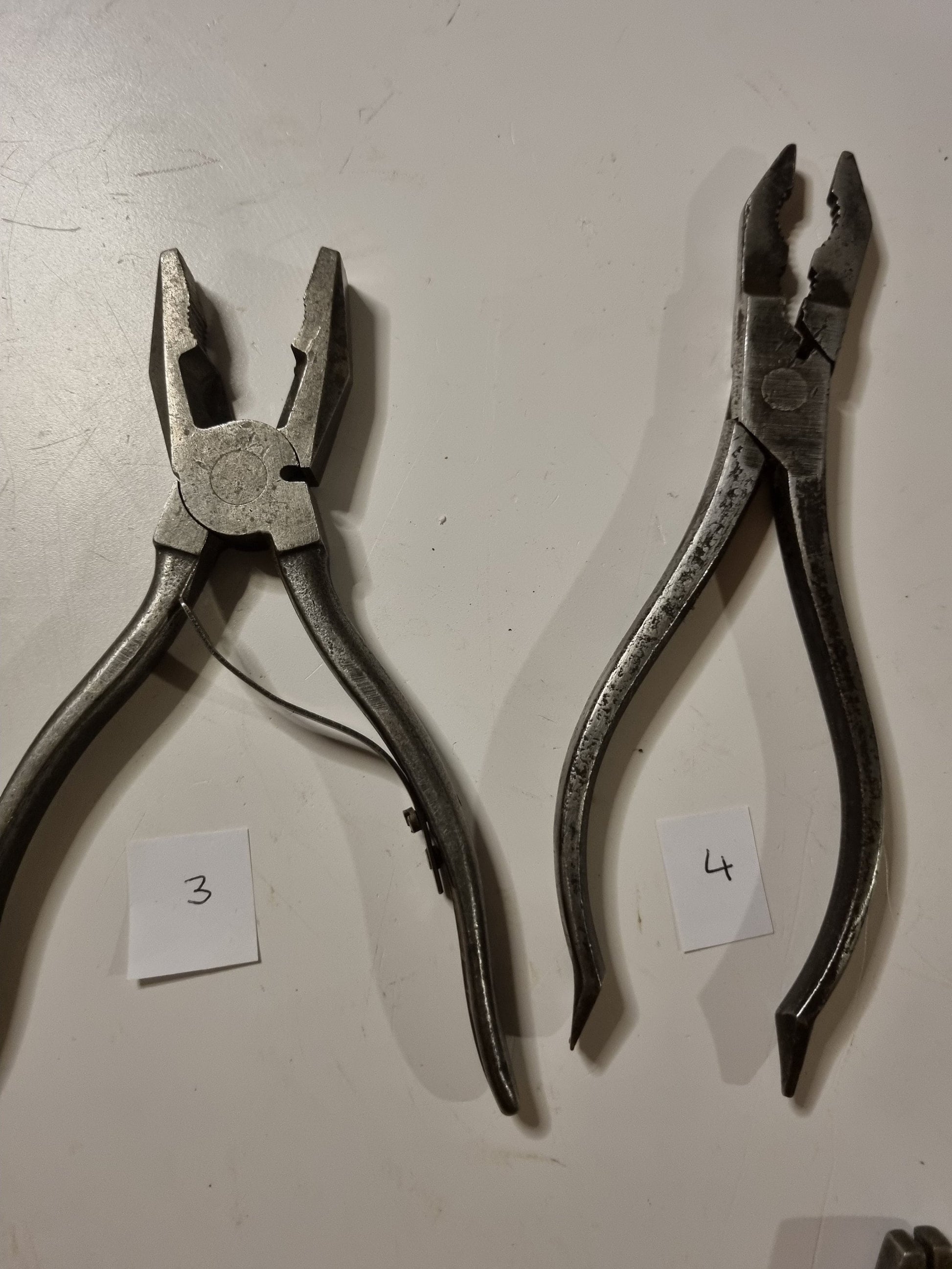 close view of vintage metal pliers titles 3 and 4 on white background