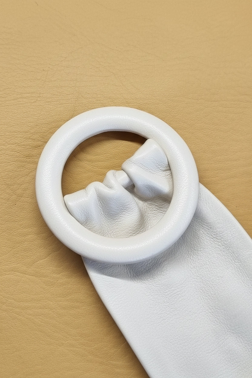 A close-up women white leather cinch belt with a leather covered ring buckle. 