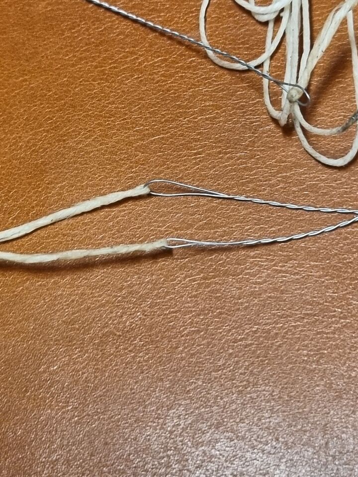 Close view of handmade pair of wire bristle attached to waxed threads for hand stitching