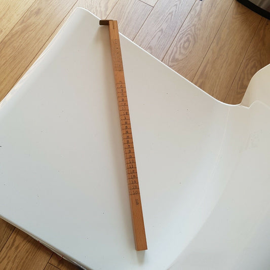 A wooden shoe size stick with brass guide, marked with English shoe size on one side and a 16-inch ruler on the other, placed on a white surface.