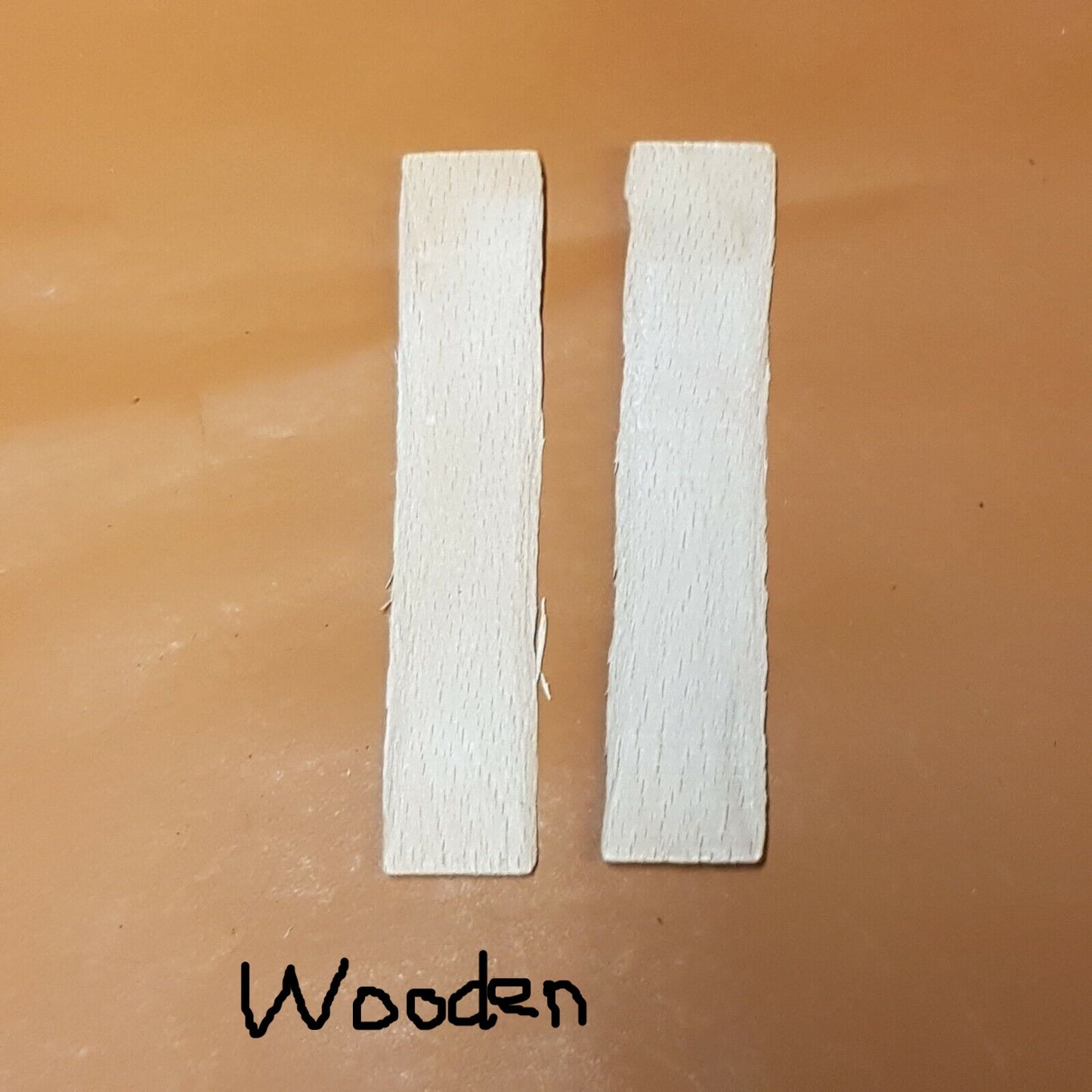 A pair of wooden shanks for boots and shoes laid on a white surface.