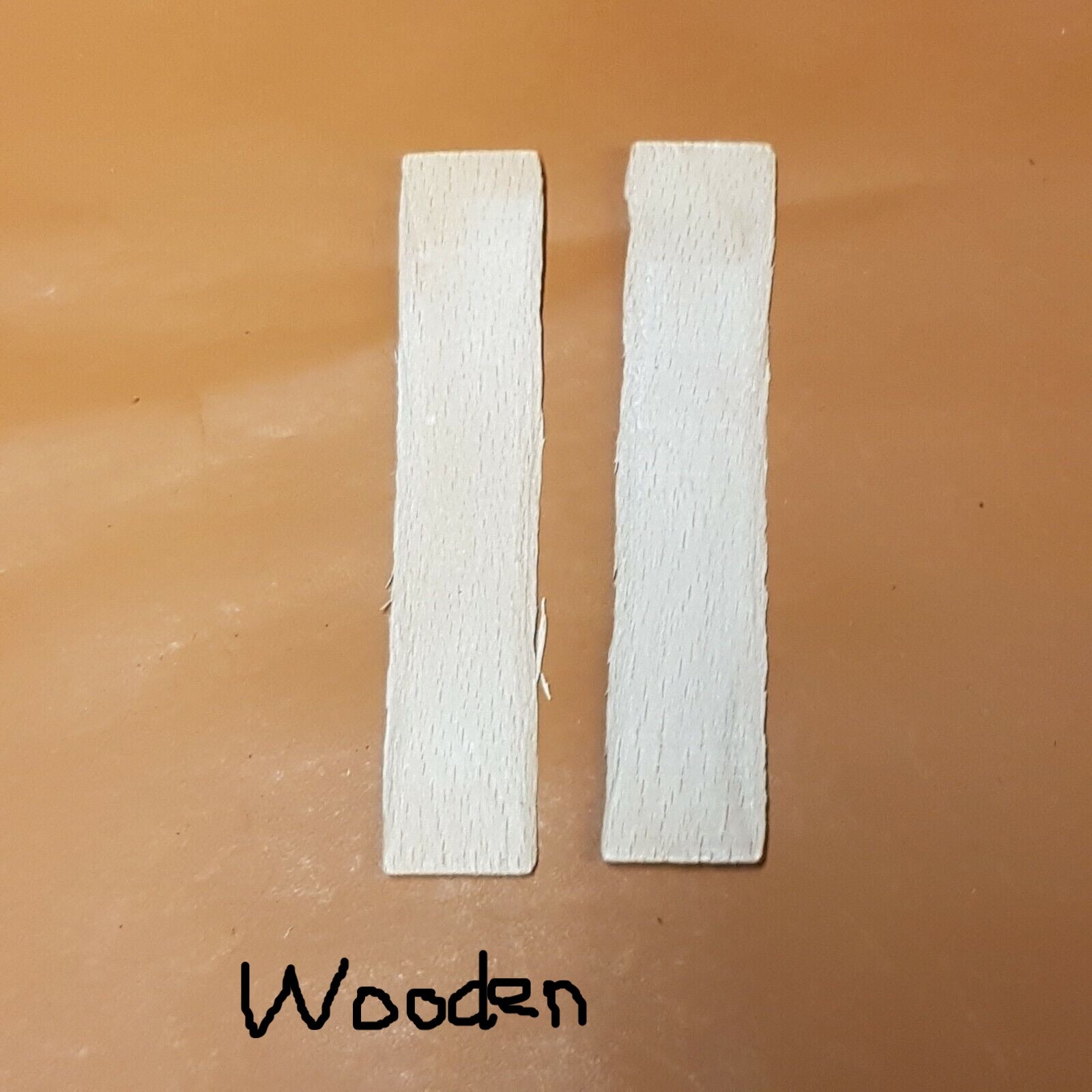 A pair of wooden shanks for boots and shoes laid on a white surface.